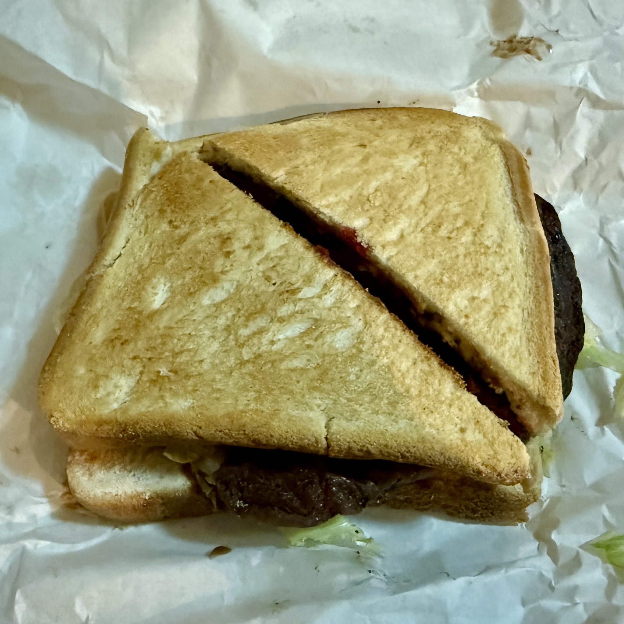 A toasted steak sandwich on white paper